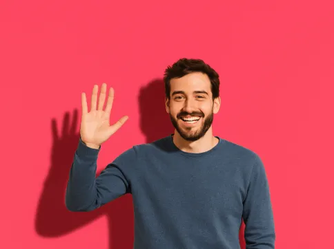 A young man with curly hair saying hello